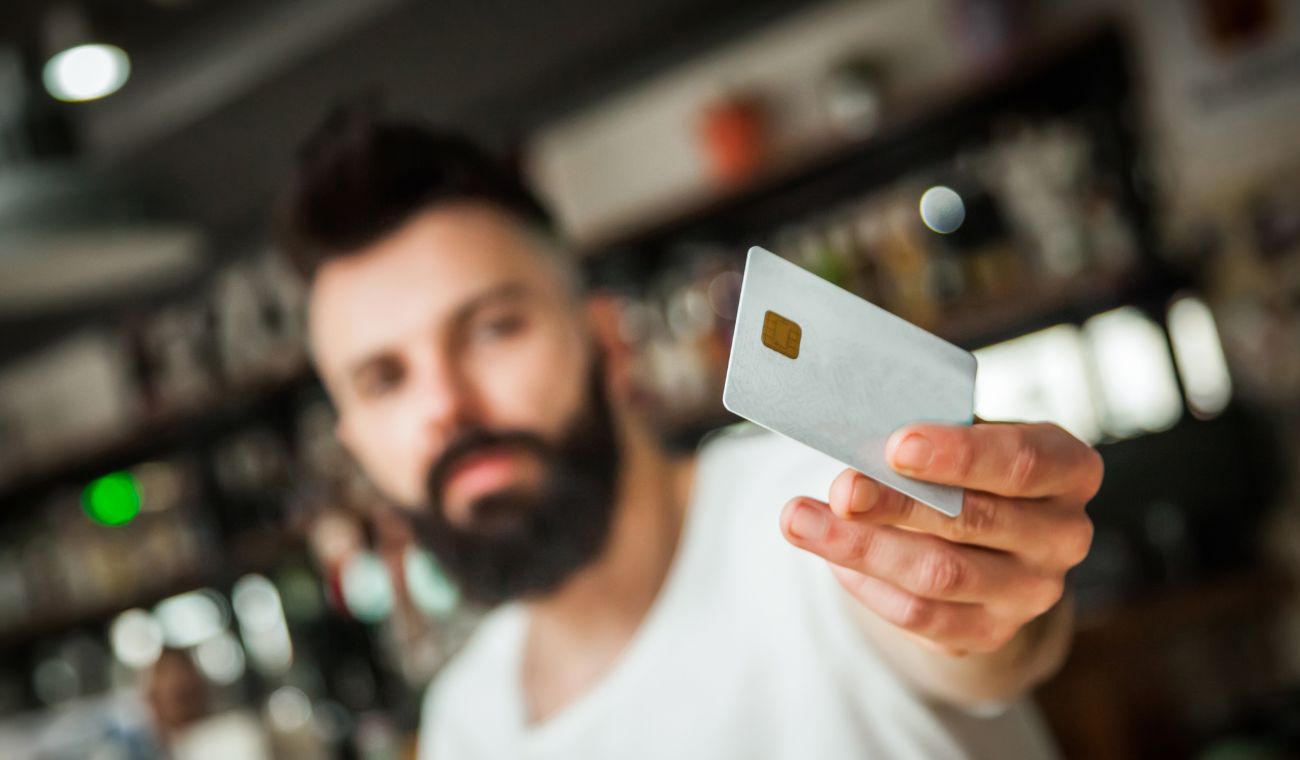 Persona sosteniendo una tarjeta bancaria con chip en un entorno borroso